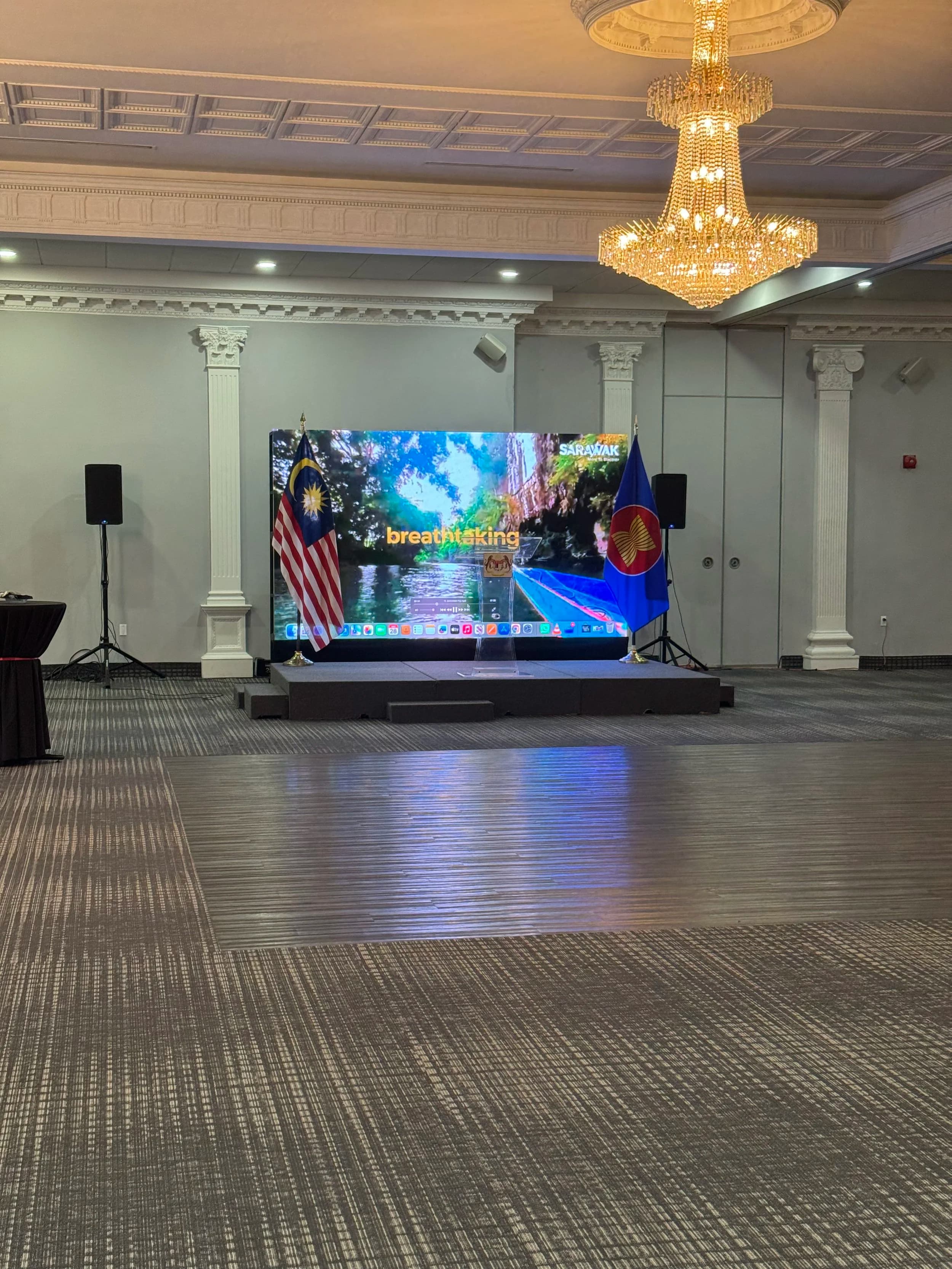 LED wall on stage at an Ottawa embassy reception with Malaysia and ASEAN flags flanking the screen