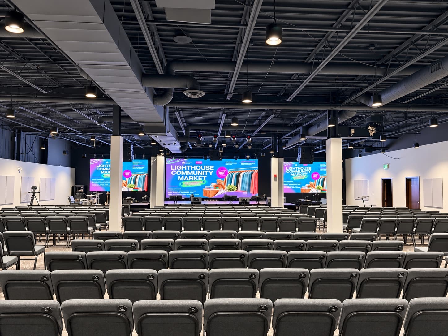 Permanent LED installation at Lighthouse Church: a large centre LED wall and two side walls above the stage, facing rows of auditorium seating